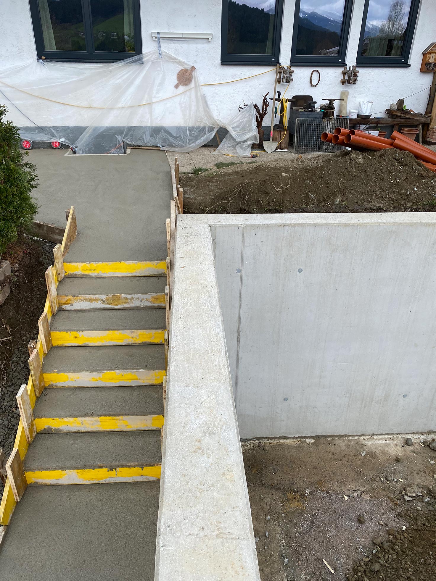 Frisch betonierte Treppenanlage an der Stützmauer für das Carport mit vier Stellplätzen in Flachau – Ausführung in Sichtbeton-Rahmenschalung, Robert Präauer / Praebau.